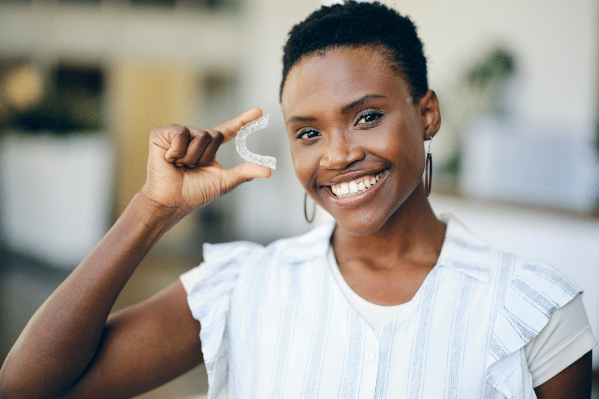 Woman holding clear retainer after Invisalign treatment in Hanover, PA