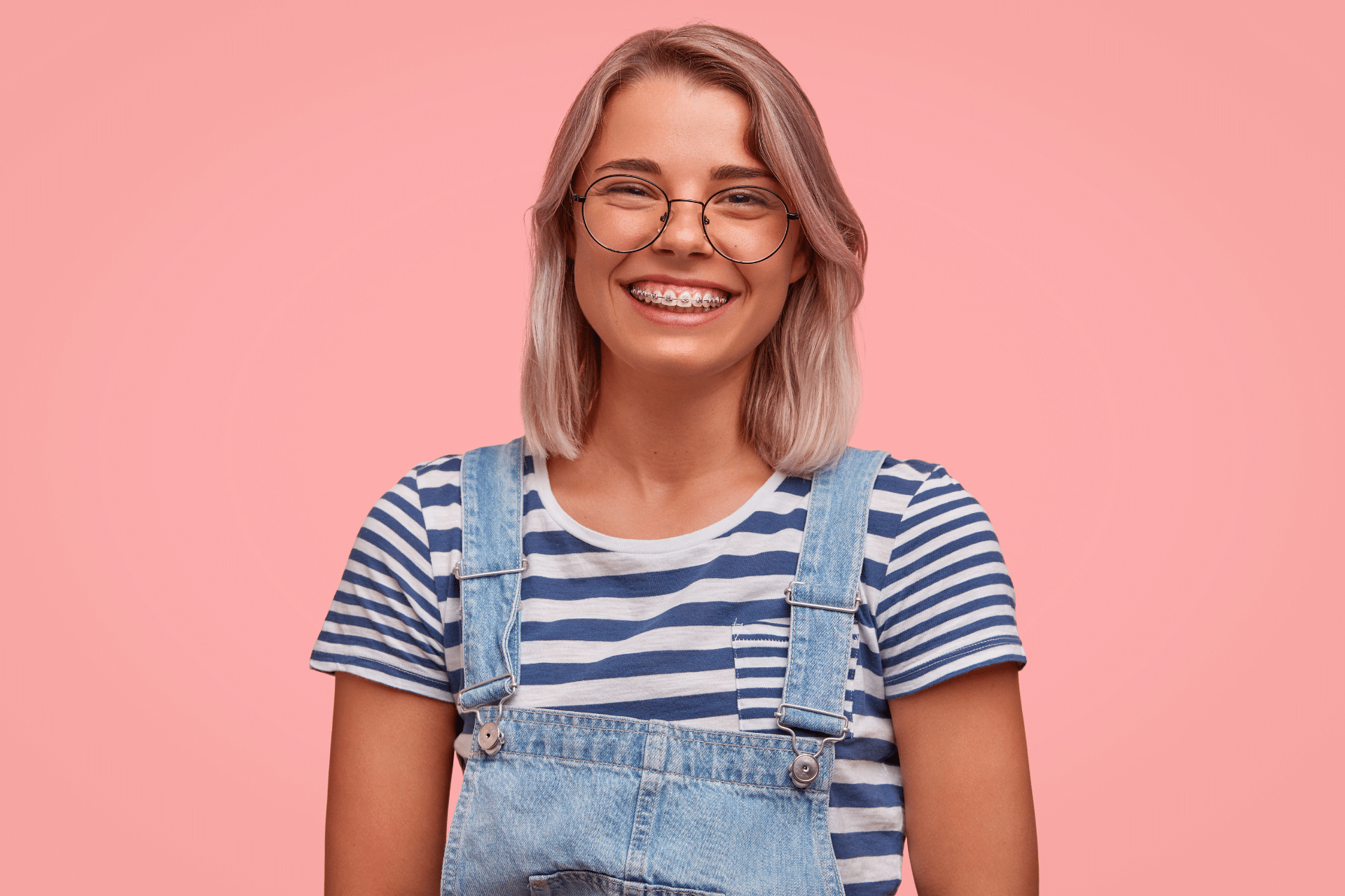 College-age woman smiling while wearing metal braces and glasses